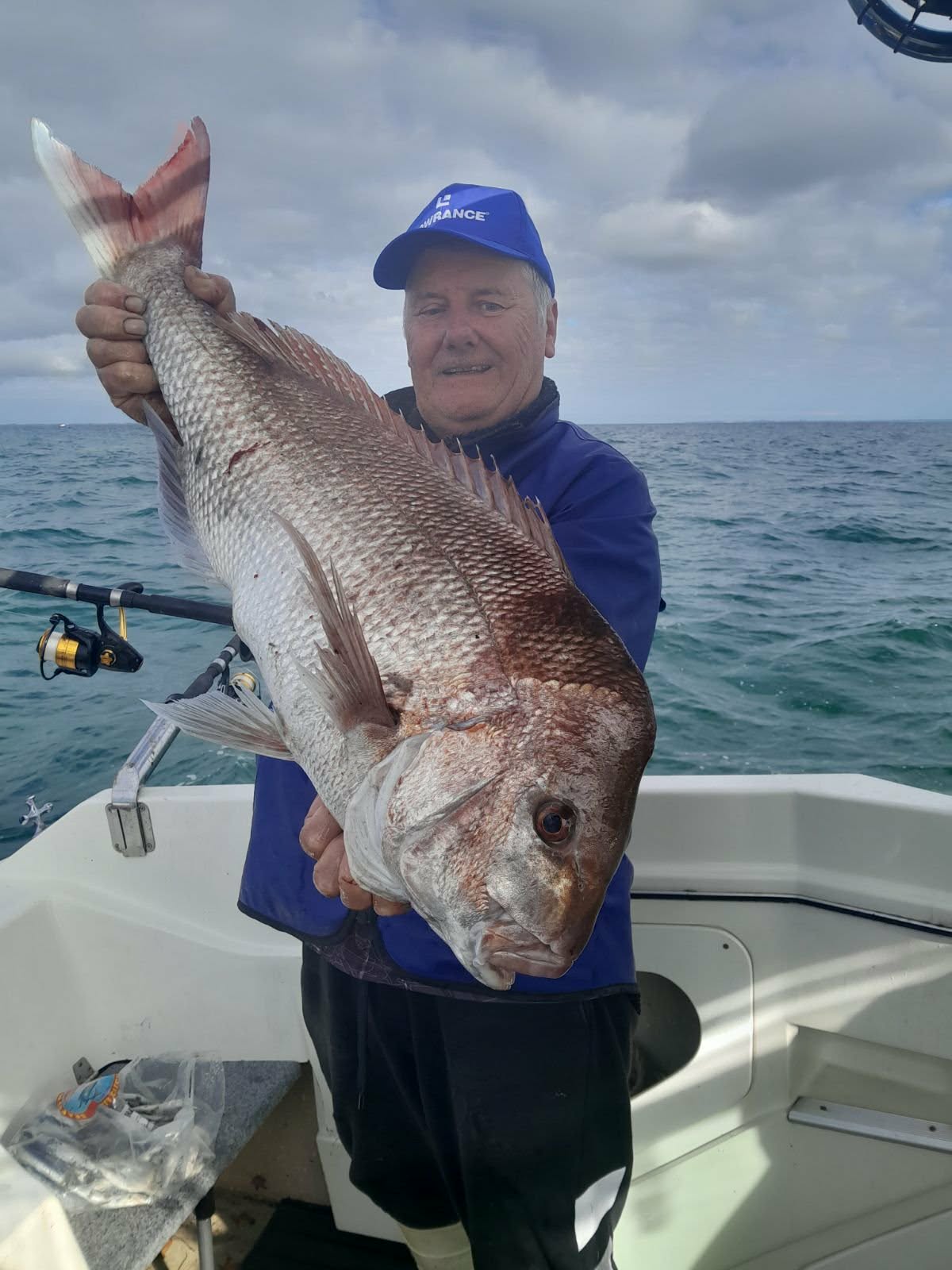 Angler holding a trophy snapper aboard a fishing boat