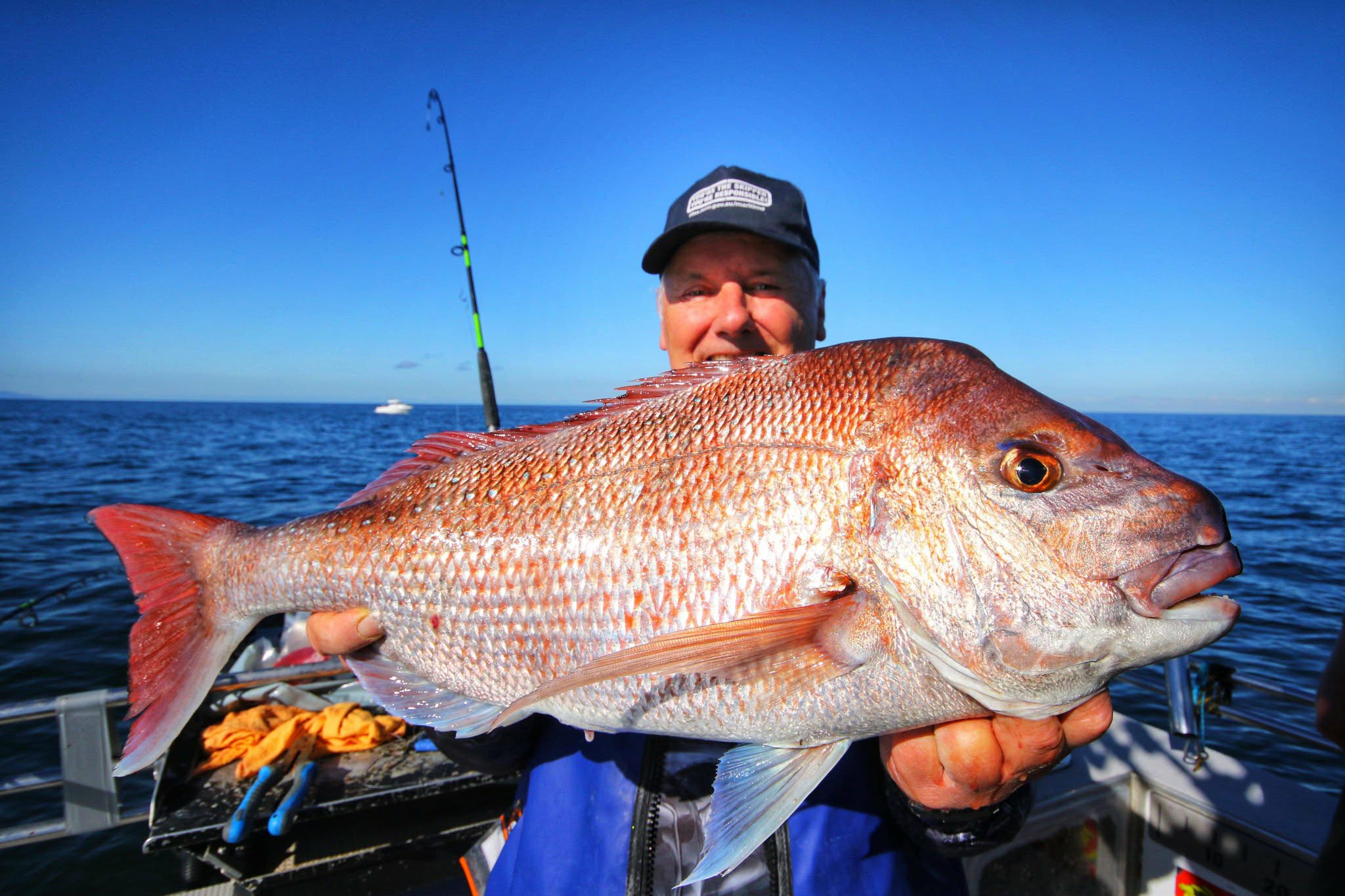 Large snapper held across the deck with open water behind