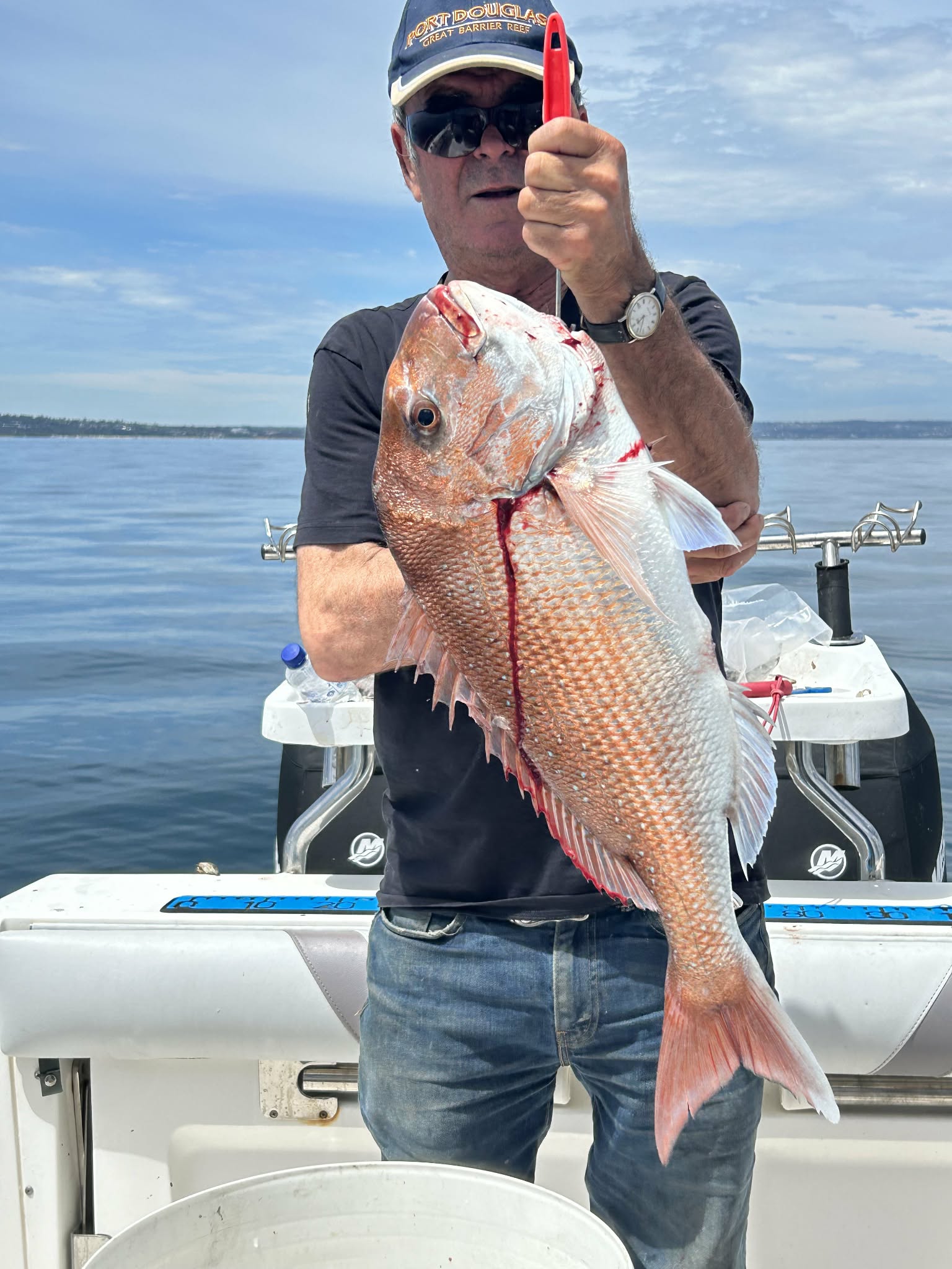 Angler holding a large snapper on calm water
