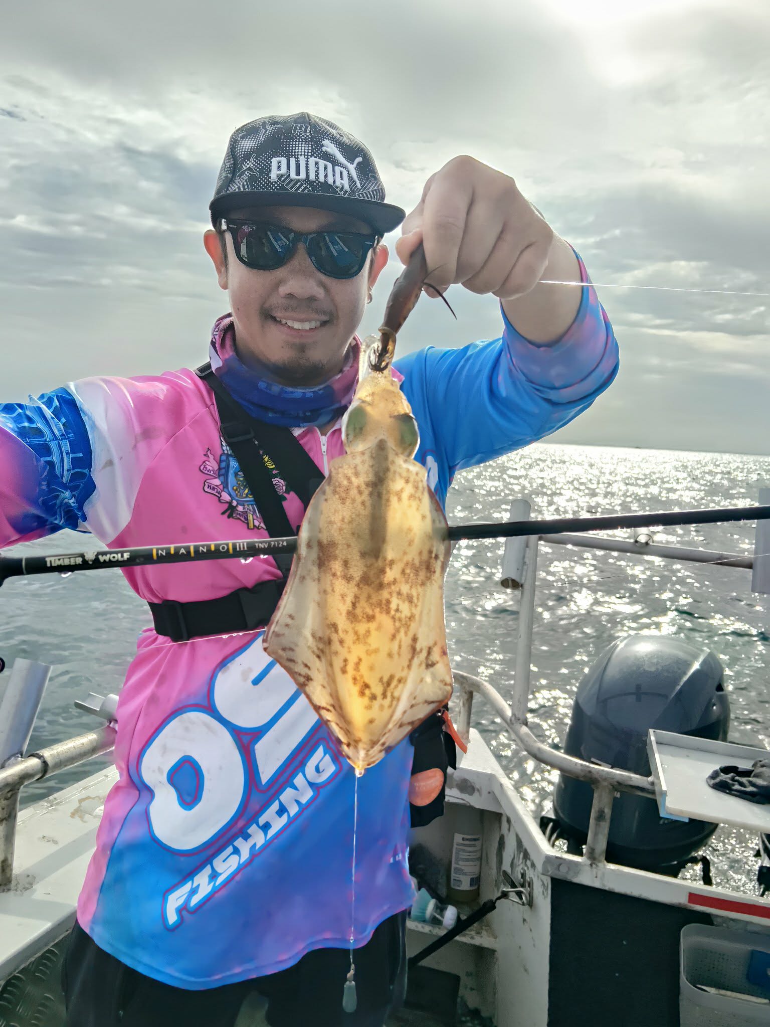 Angler in bright fishing gear holding a squid