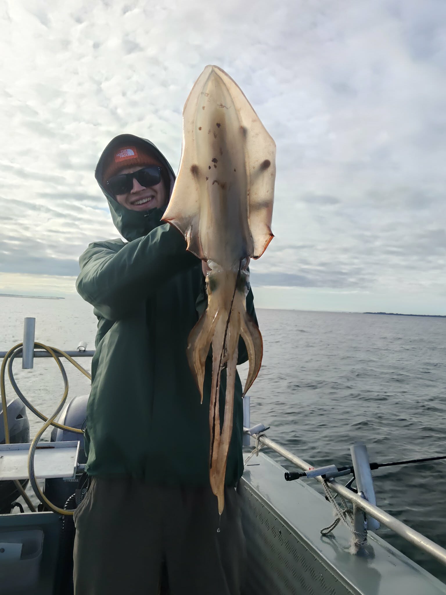 Angler holding an exceptionally large squid aboard the boat