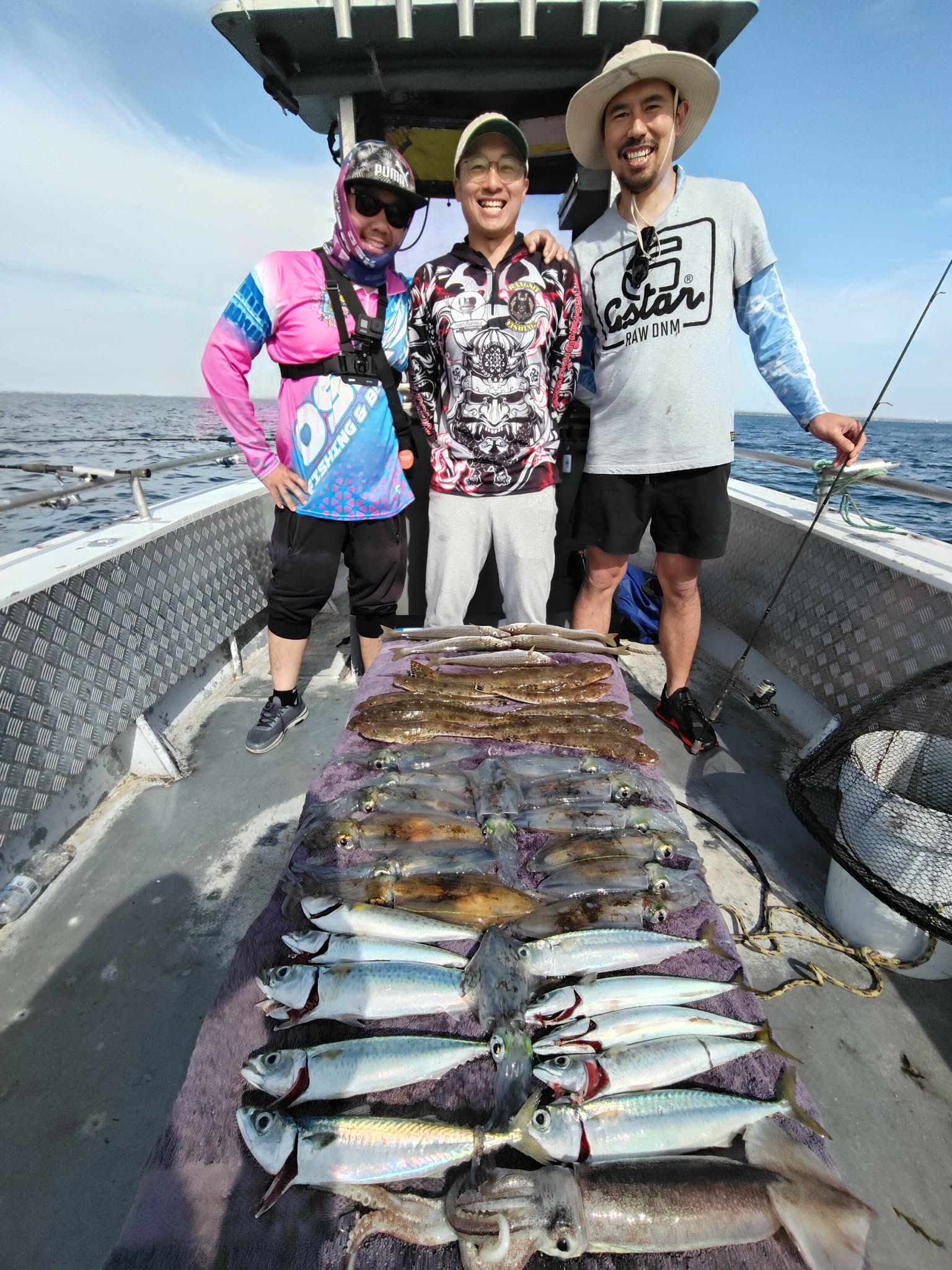 Three smiling anglers behind a varied catch laid out on deck