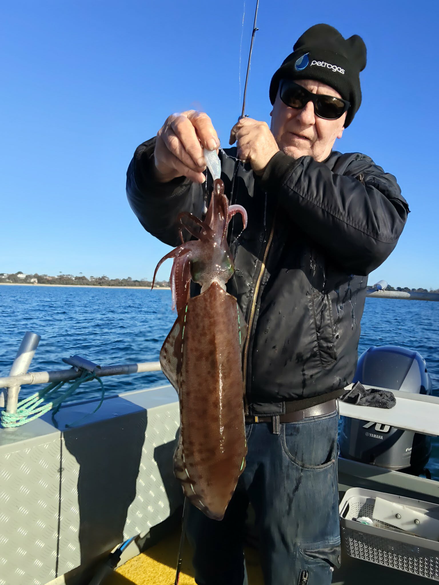 Angler holding a large squid against blue sky and water
